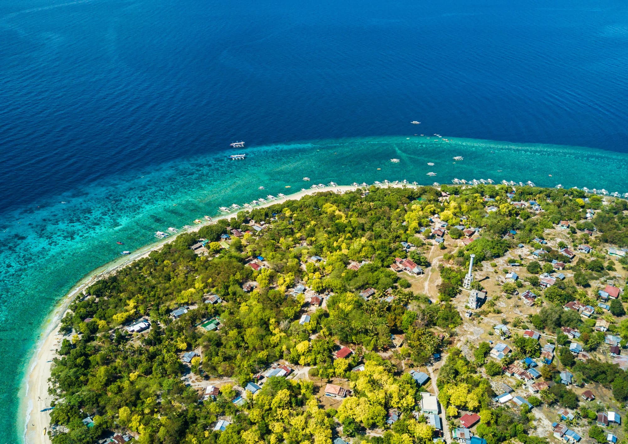 Drone view of a tropical island surrounded by turquoise water and coral reefs in the Visayas.
