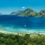 Panoramic view of Las Cabanas Beach in El Nido, Palawan, Philippines, with turquoise water, tropical islands and lush green coastline.