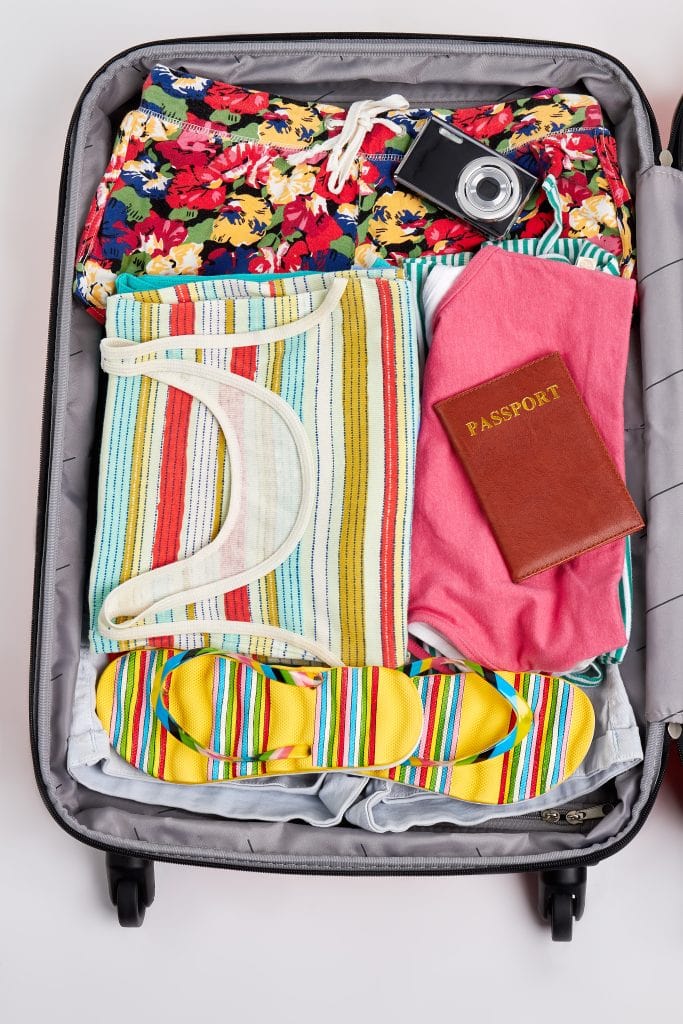 Open suitcase neatly packed with clothes, travel essentials and a passport.
